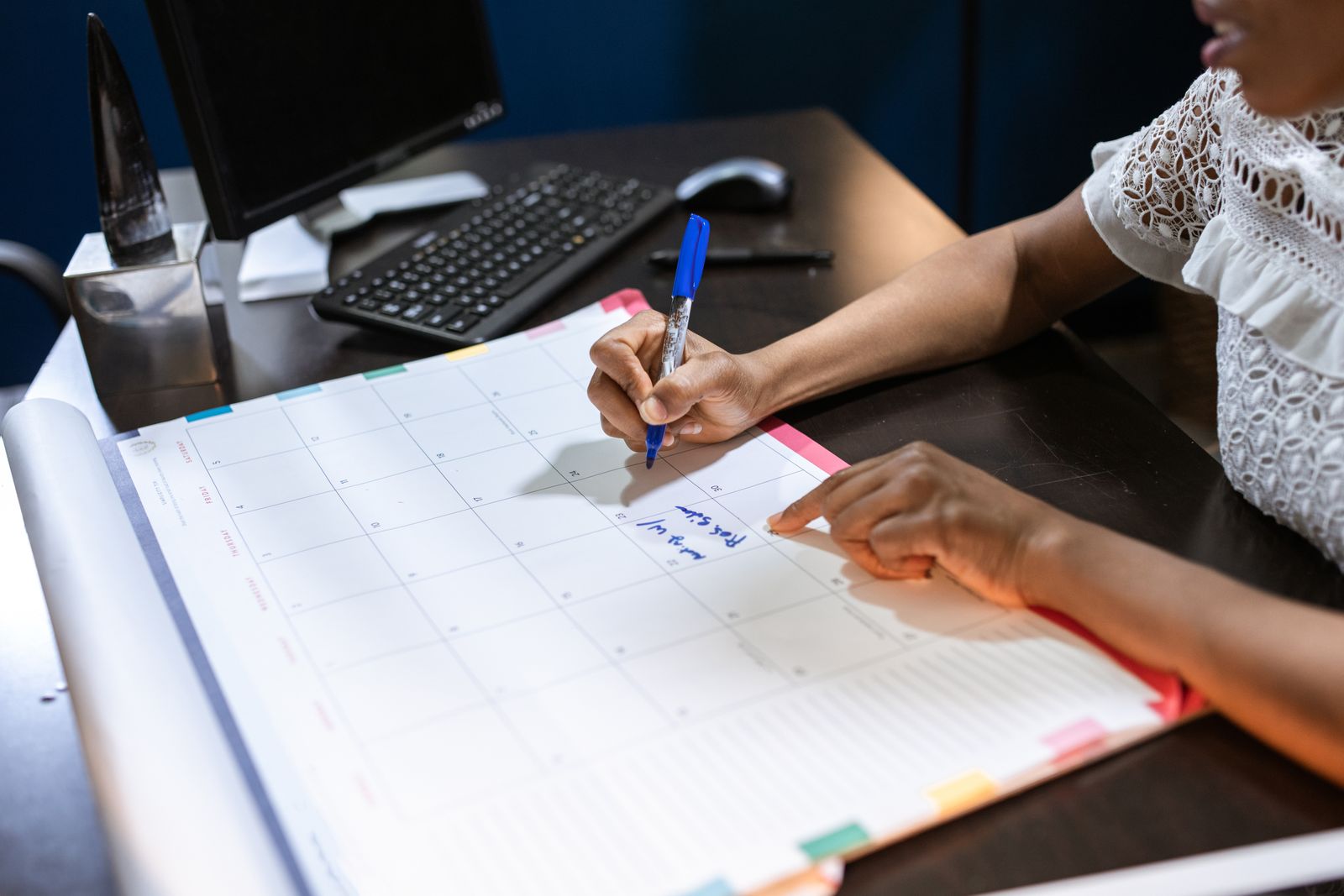 Pessoa anotando compromissos em planner sobre a mesa
